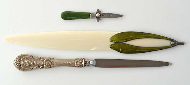 Top: An assortment of wooden paper-knives from Spellerberg's collection. From top to bottom, bamboo knife with a ruler; a curved (sickle shape) Mauchline ware paper-knife with poker and transfer work; an olive wood paper-knife inscribed "The Mount of Olives" in Hebrew; a walnut paper-knife hallmarked 1881 and featuring a wooden soldier’s head carved from a palm nut. Above: Letter openers are often made from precious materials. From top to bottom, a greenstone and silver opener from 1903; an Art Nouveau ivory opener with enameled silver; and a letter opener featuring a sterling silver handle.