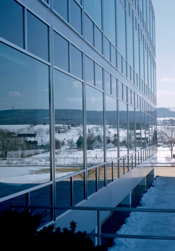 A glass facade reflects the rural surroundings of Connecticut General's new Bloomfield office, circa 1950s. Via <a href="https://dome.mit.edu/handle/1721.3/29817">MIT Libraries</a>.