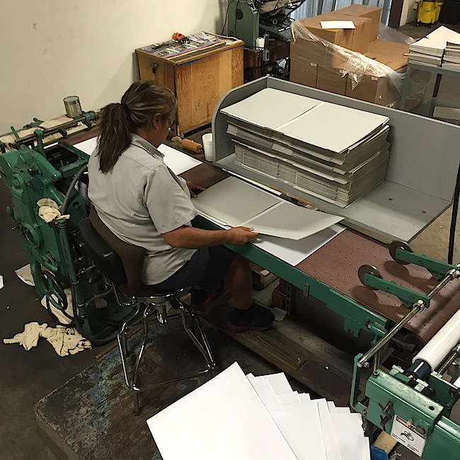 Here, a Stoughton employee mounts the outside cover onto what will eventually be a gatefold jacket.