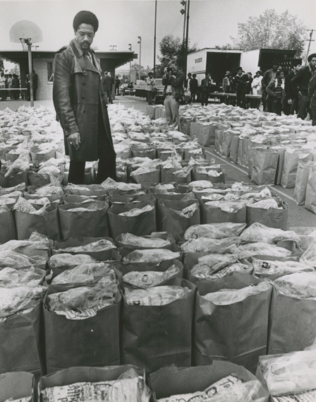 Black Panther leader Bobby Seale inspects bags of groceries the organization has prepared to hand out to impoverished families in Oakland, on March 31, 1972. Photo by Howard Erker. (Courtesy of the Oakland Museum of California, the "Oakland Tribune" collection)