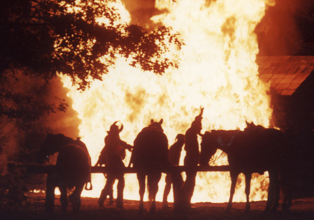 Top: A man wears the only known remaining Bald Knobber mask, belonging to William James of St. Louis. (Courtesy of The State Historical Society of Missouri) Above: Bald Knobbers set a cabin on fire in "The Shepherd of the Hills" outdoor drama, a play that's run 57 years in Branson, Missouri. In reality, arson was not a Bald Knobber calling card. (Via BransonHotline.com)