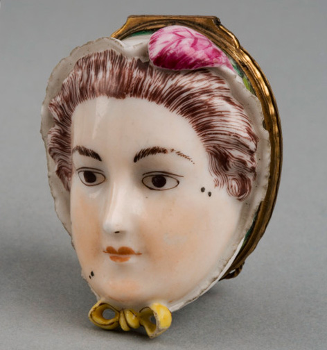A patch box in the shape of a fashionable woman's face, replete with her own beauty marks. Via the Victoria & Albert Museum