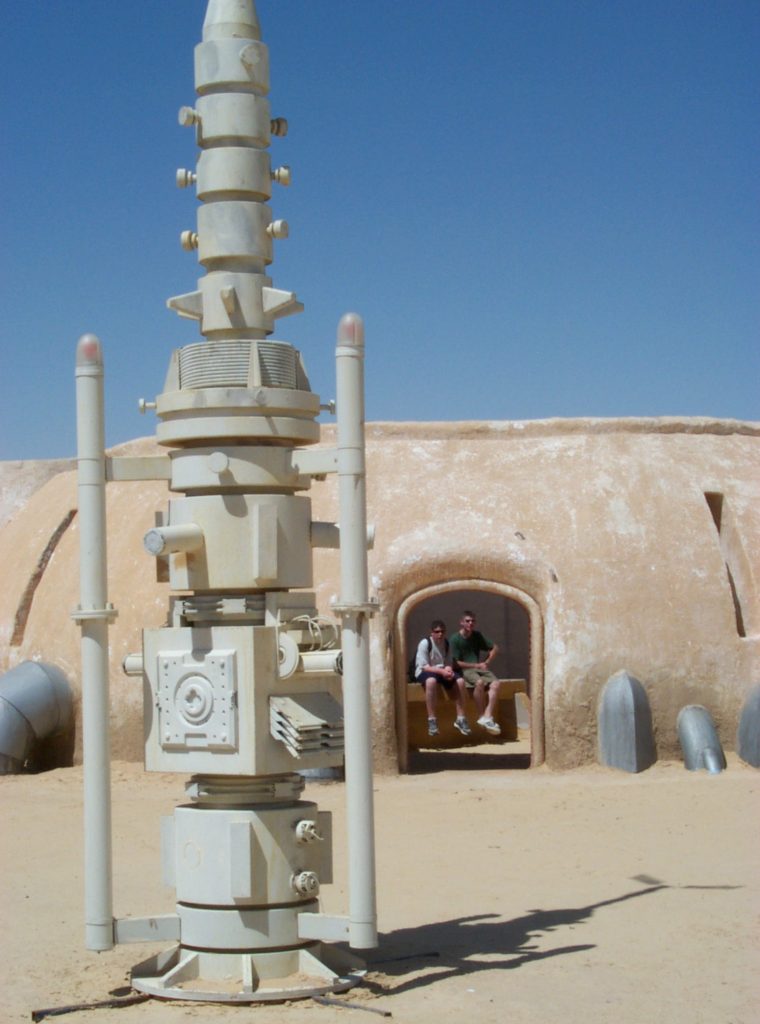Alinger and his younger brother sat in Watto's parts shop (made of wood and plaster) on the set of Mos Espa near Tozeur, Tunisia, in 2001, just a few months after the second prequel finished filming there. In the foreground is a moisture-vaporator prop (made of wood) that, in the movie, was used to supply water to the desert planet. This set, a popular tourist site seen in "The Phantom Menace" (1999) and "Attack of the Clones" (2002), is now threatened by sand dunes. (Courtesy of Brandon Alinger)